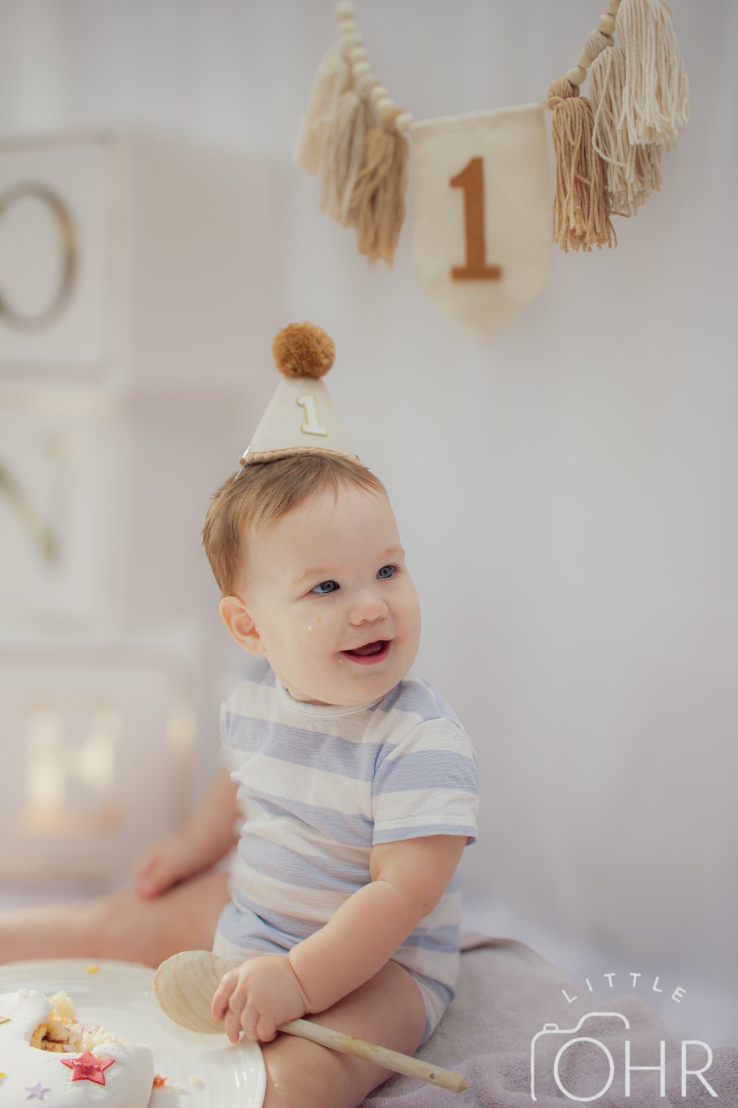 Smiling baby in a party hat beside ONE letter blocks and number one bunting