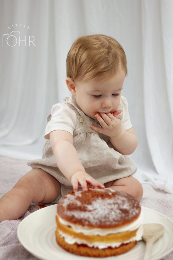 Baby reaching for a first birthday cake