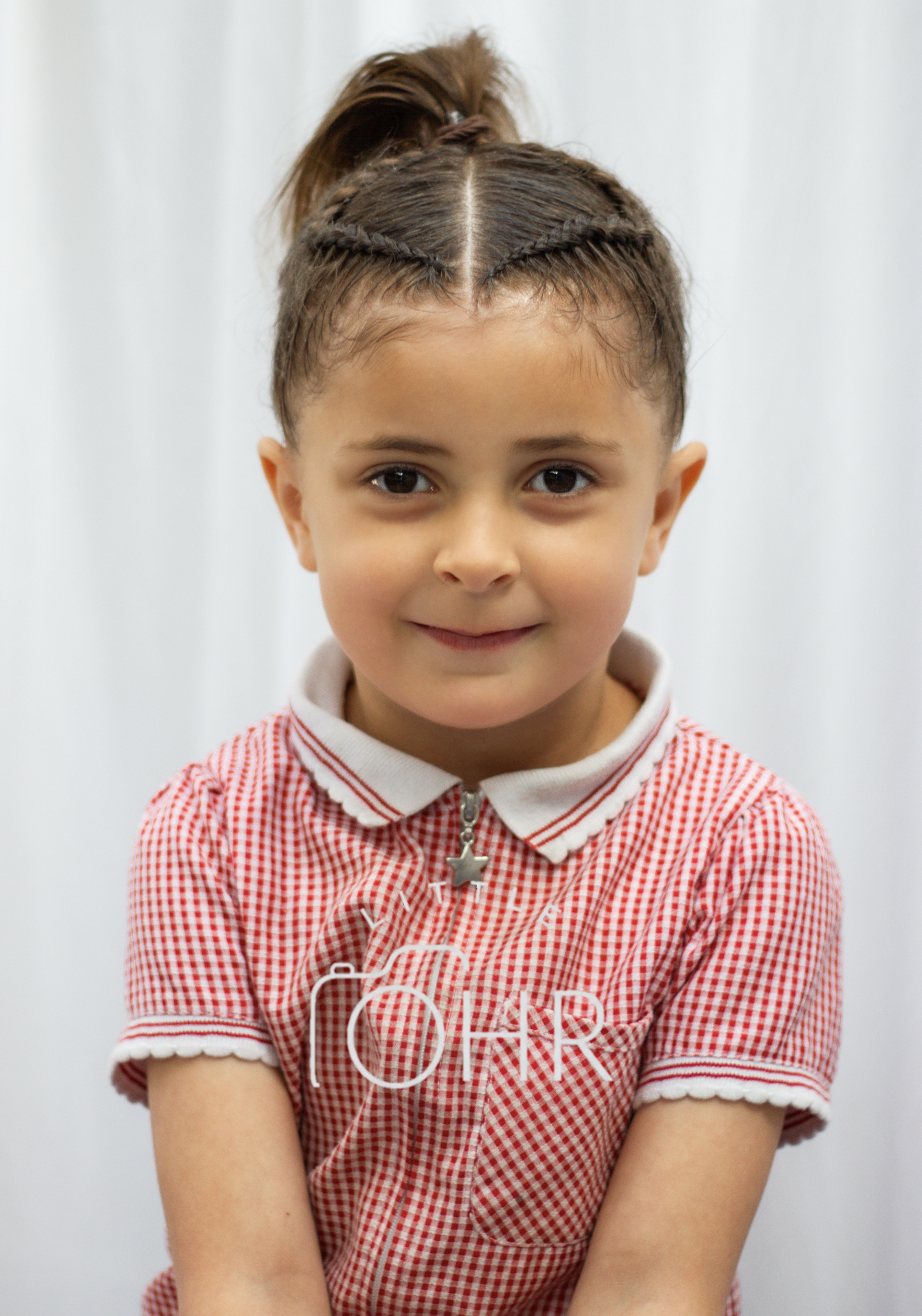 Girl in a red gingham school summer dress smiling in the studio