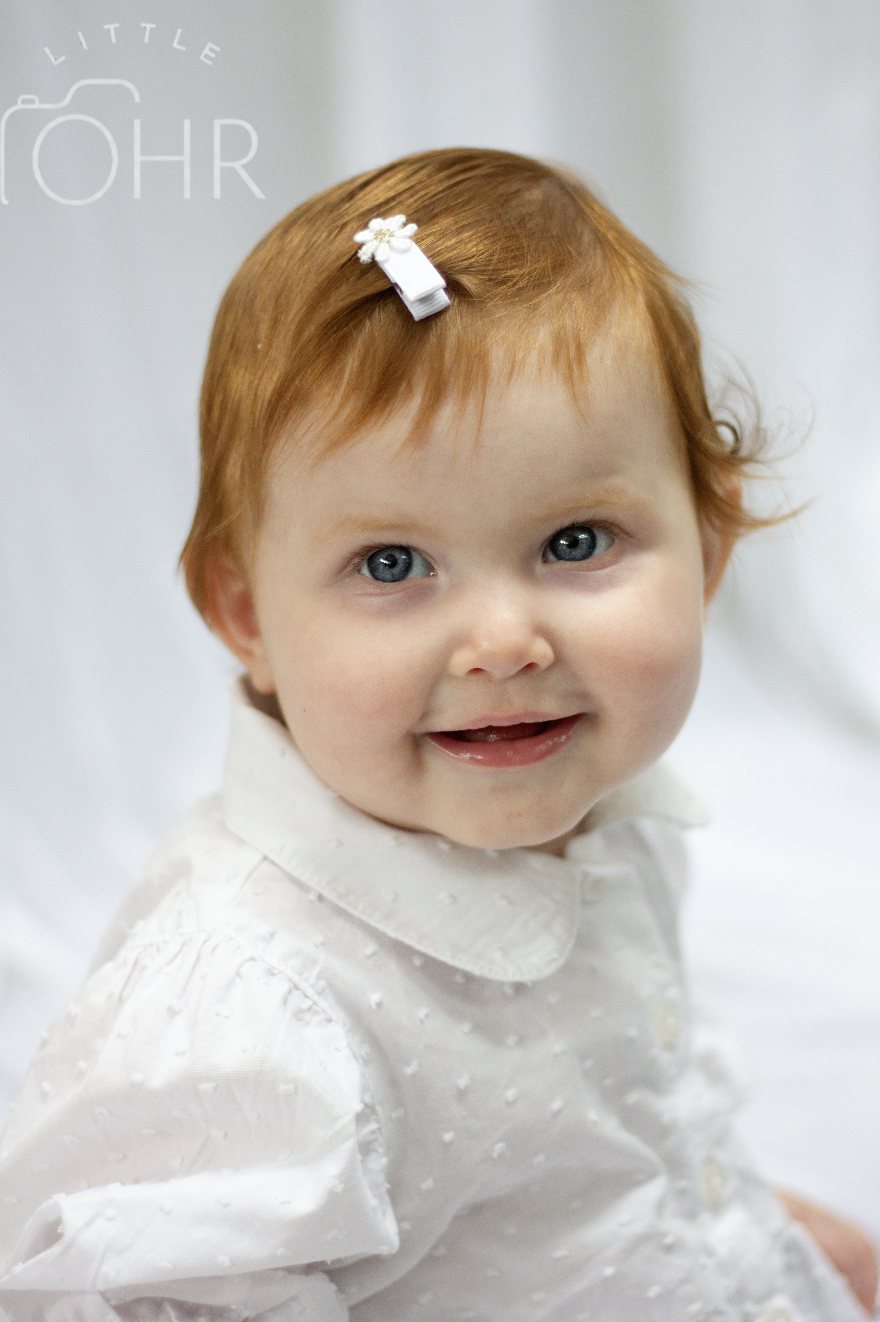 Close up of a smiling baby girl with a flower hair clip