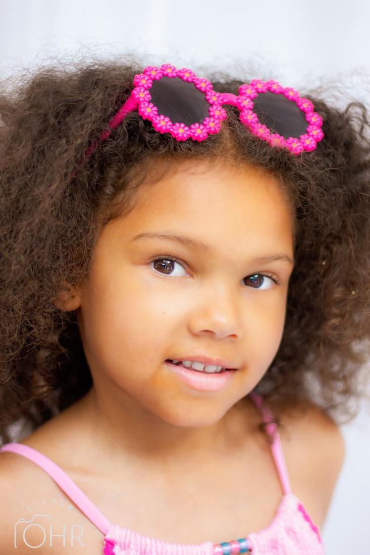 Close up of a girl with pink flower sunglasses in her hair