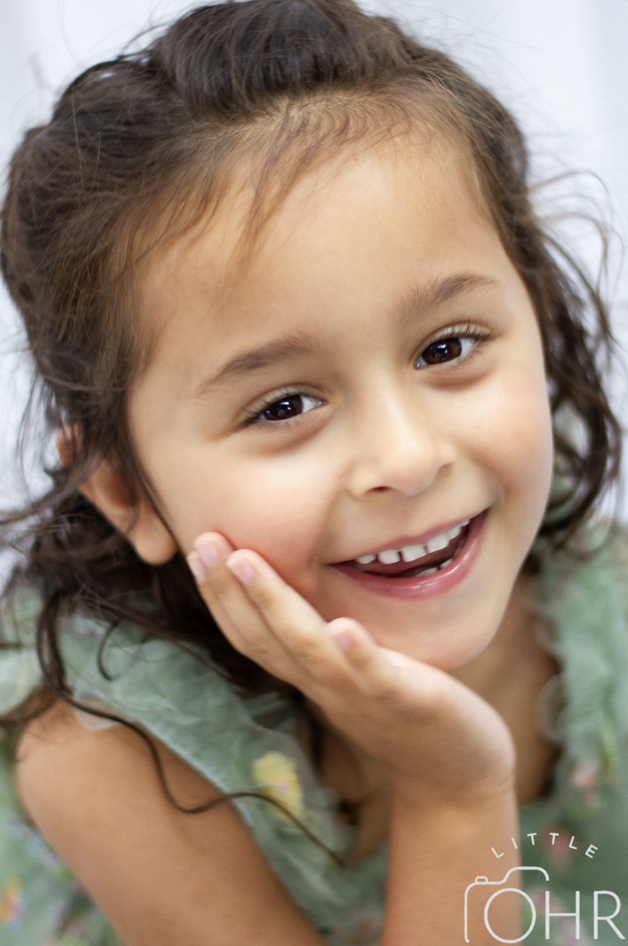 Close up of a young girl resting her cheek on her hand, laughing
