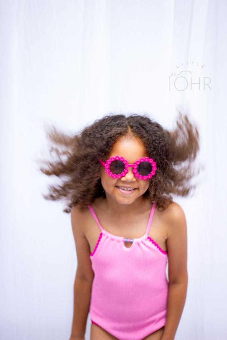 Girl in pink flower sunglasses flipping her hair