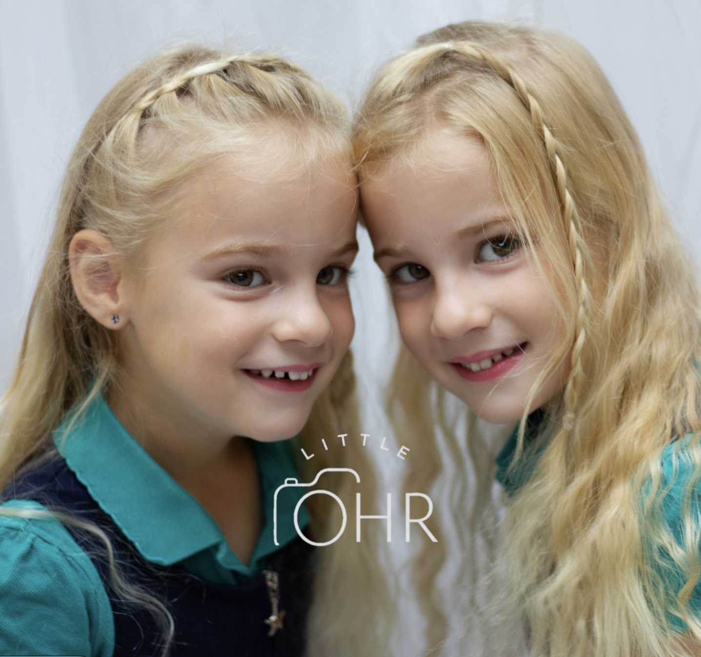 Twin sisters with plaited hair resting their heads together